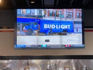 A large screen tv with a bud light truck on it.